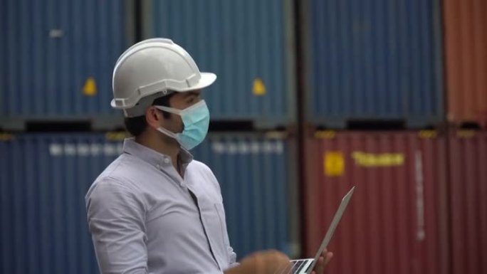 工头存放医用防护面罩，在货物仓库物流处存放笔记本电脑检查集装箱箱。在冠状病毒大流行或covid 19