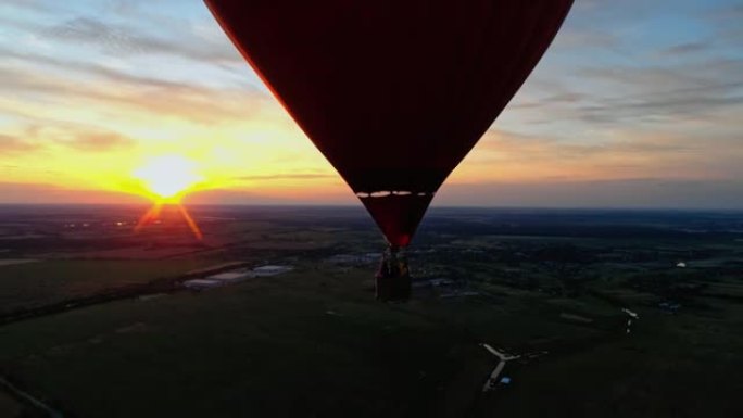 人们乘坐热气球旅行。美丽的红色浮空器，以心脏的形式在橙色日落的天空中飞行。