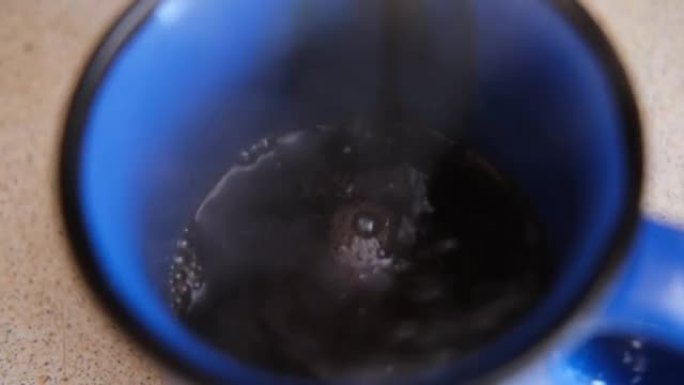 将热咖啡倒入蓝色杯子中。