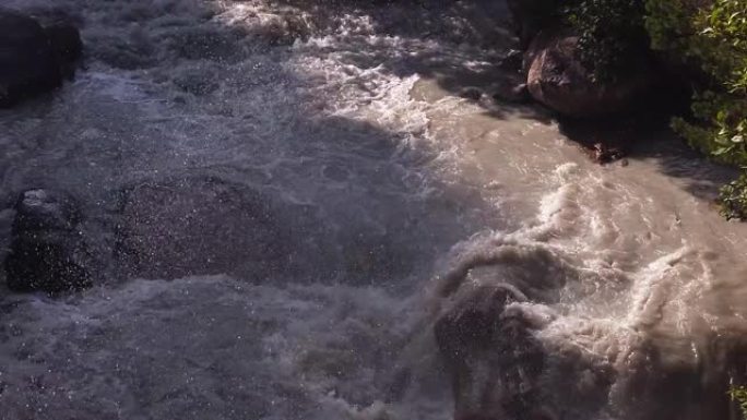 暴风雨的河水冲刷着大石头，喷雾和泡沫在飞舞。慢动作视频