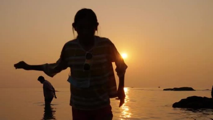 在泰国华欣度假期间，快乐的孩子们在海滩上放松，与日出一起放松。