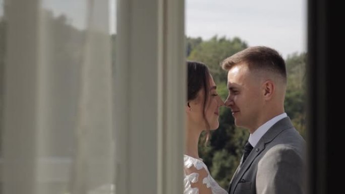 高加索新婚新娘在酒店房间的阳台上拥抱新郎，慢动作
