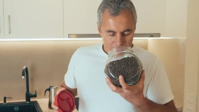 Middle aged man holds a jar of coffee beans. Jar o