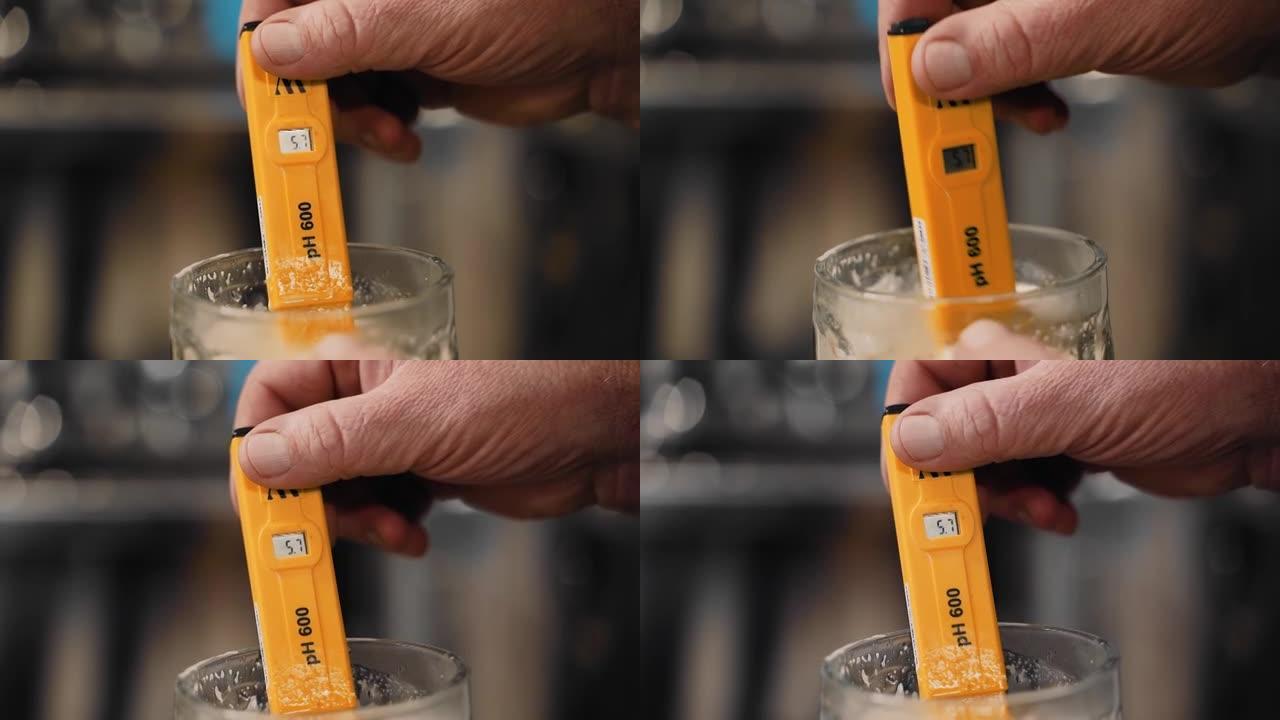 一名男子将酒精测量仪浸入新鲜酿造的啤酒中，以测量酒精的百分比。酒精饮料的制备。特写拍摄