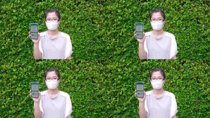 在绿色背景下在智能手机上显示数字疫苗护照验证新型冠状病毒肺炎的妇女