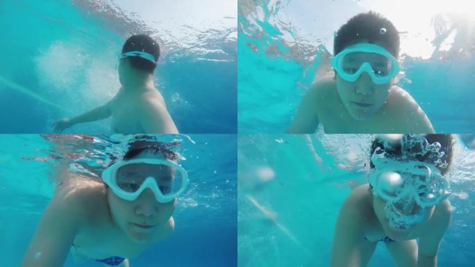 快乐的亚洲男孩夏天在公共游泳池游泳，在水景下。