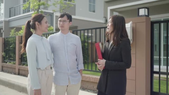 亚洲女性房地产经纪人向年轻的亚洲夫妇情人展示了她档案中的房屋细节，并有兴趣购买它。买一栋新房子。