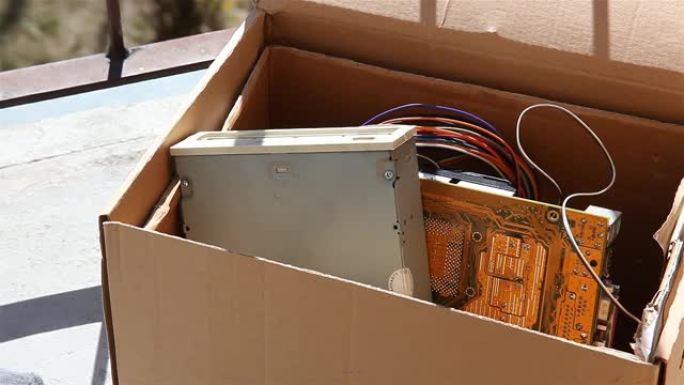 扔掉电子垃圾，一名男子将旧的过时pc组件放入一个盒子中，将其关闭并带走，电子垃圾回收，旧计算机零件垃