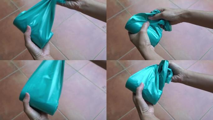 女人从一卷里撕下新的蓝色塑料袋。塑料袋消费理念。