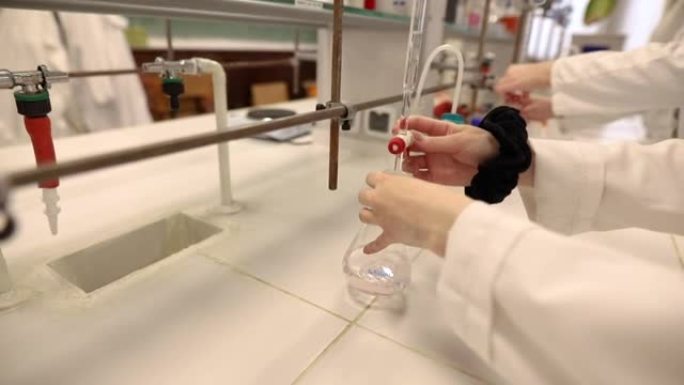 化学学生在滴定过程中用液体溶液填充实验室烧瓶