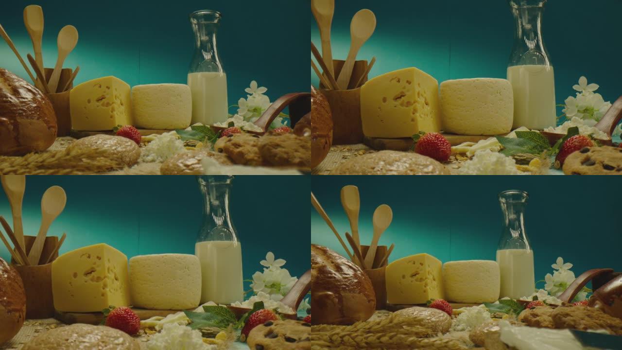 蓝色背景上装饰有乳制品和烘焙产品的精美组成。用奶酪，牛奶，面包，饼干，小麦，草莓和厨具准备的桌子。特
