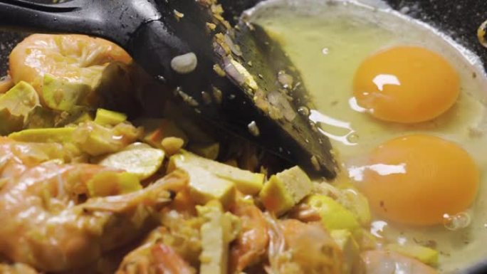 有人把鸡蛋放在平底锅里的泰式菜单上。泰国最喜欢的菜。用米粉、豆腐、虾、罗望子酱等制成。