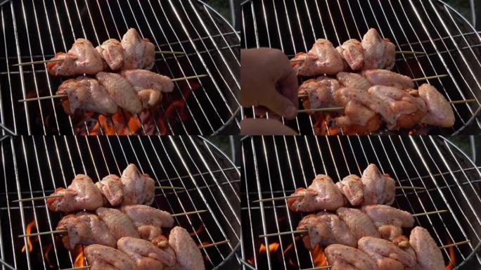 雄性的手在烤架上放了一个带有生鸡翅的木串