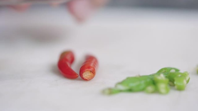 厨师将红色和绿色的辣椒压碎并切成小块。