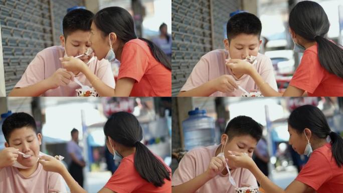 亚洲儿童在小路或街头食物上一起吃冰苏。(该小吃在韩国非常受欢迎)，将水果和糖浆的刨冰放在杯子中。