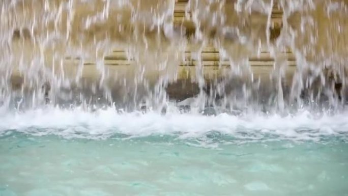 旧黄色大理石喷泉水幕的特写。透明的水流。夏季晴天