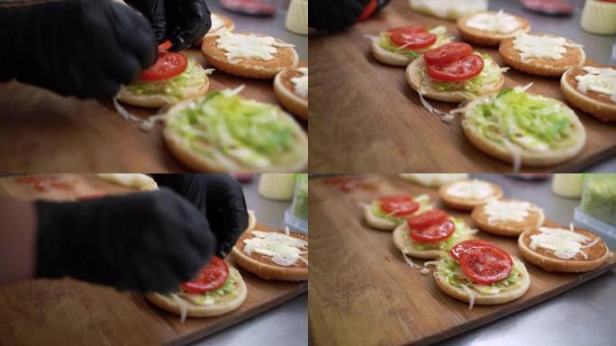 汉堡由面包，肉排，蔬菜和酱汁制成。儿童节日菜单。大厨将西红柿放在面包上的特写镜头。