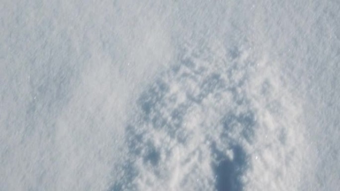 穿着冬天的衣服和保暖的鞋子的脚在森林的雪地里穿行，在一个霜冻的晴天向不同的方向撒雪。相机从上方拍摄。