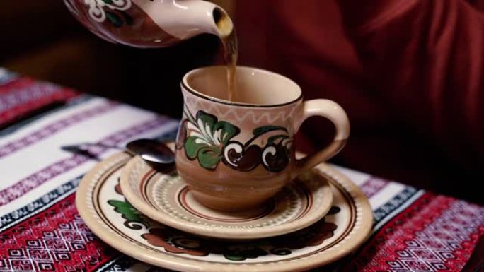 茶。一只手将茶从茶壶倒入杯子中。
