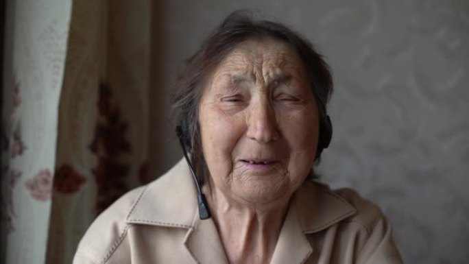 戴着耳机的非常老的女人在家里进行视频对话。视频对话概念。在线爆头。