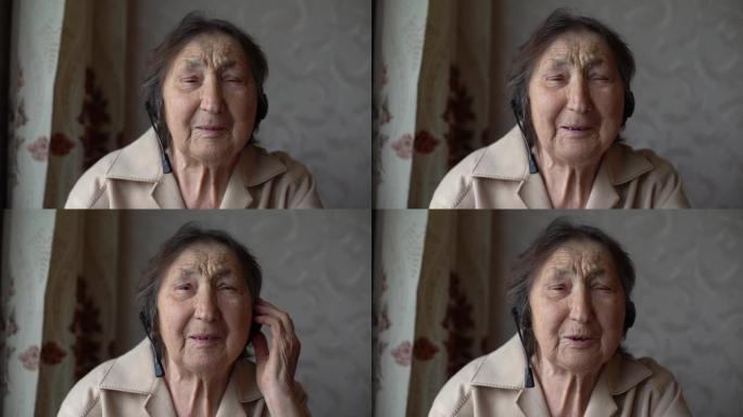 戴着耳机的非常老的女人在家里进行视频对话。视频对话概念。在线爆头。