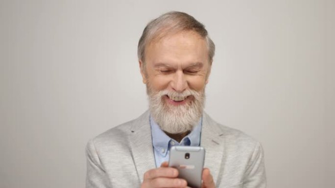 微笑的男人拿着手机在里面。老年绅士在室内看电话。