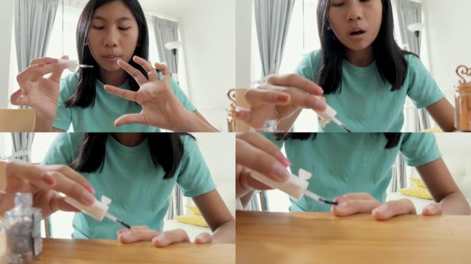 快乐的亚洲女孩在家用指甲油画她的手指，生活方式的概念。