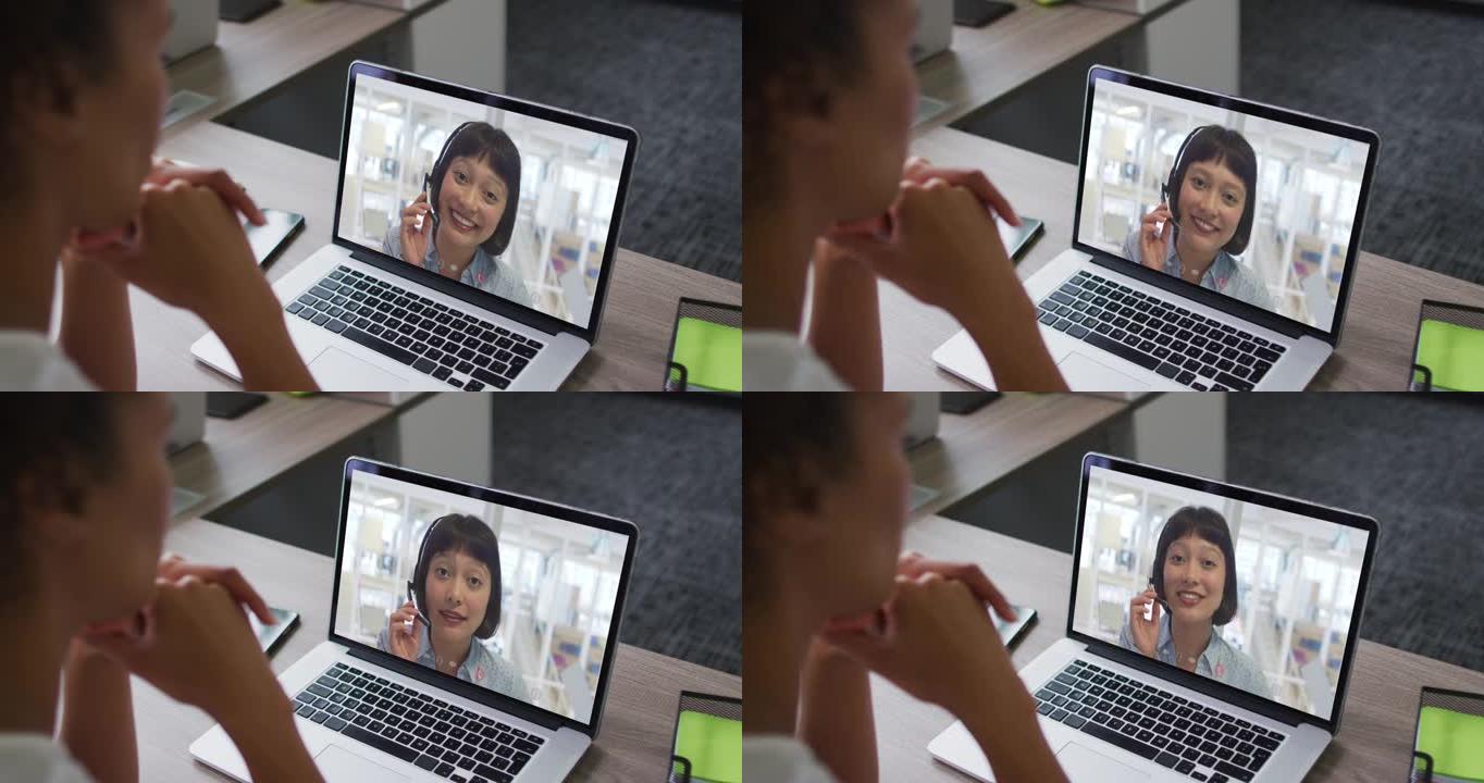 非裔美国女商人坐在办公桌前，用笔记本电脑与女同事进行视频通话