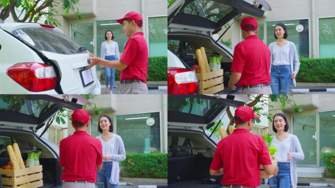 穿着红色制服的亚洲邮递员在家给年轻可爱的女孩送杂货盒。迷人的女人带着微笑的脸处理食物，用信用卡敲击机