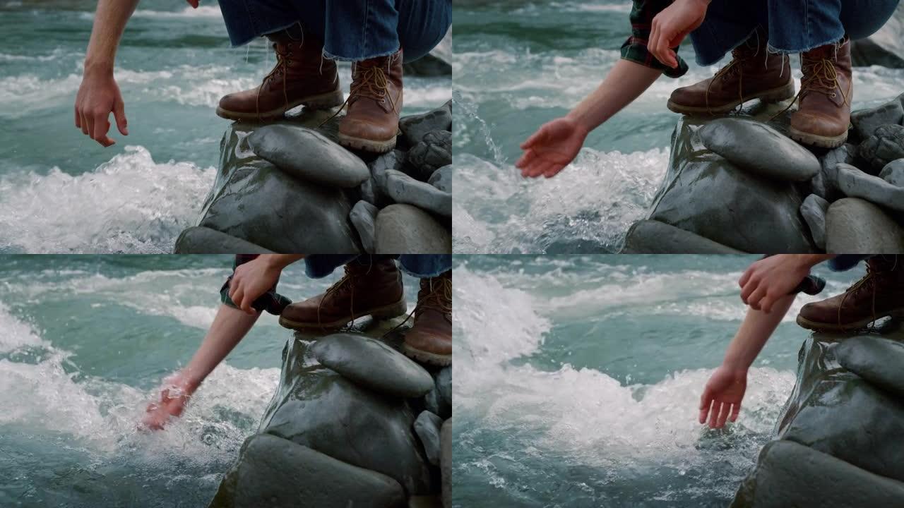 坐在溪流岩石上的人。男性手触摸河水中的淡水