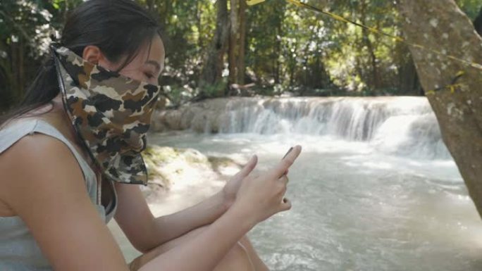 东南亚女子在瀑布戴防护口罩