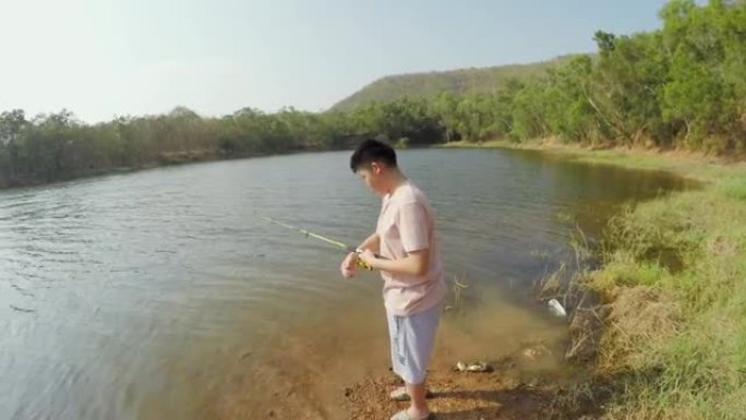 亚洲男孩在度假期间与家人在湖边钓鱼，生活方式理念。