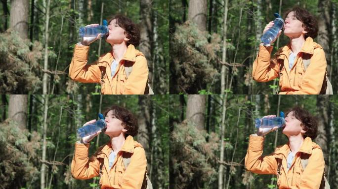 女人在阳光明媚的森林散步时喝水