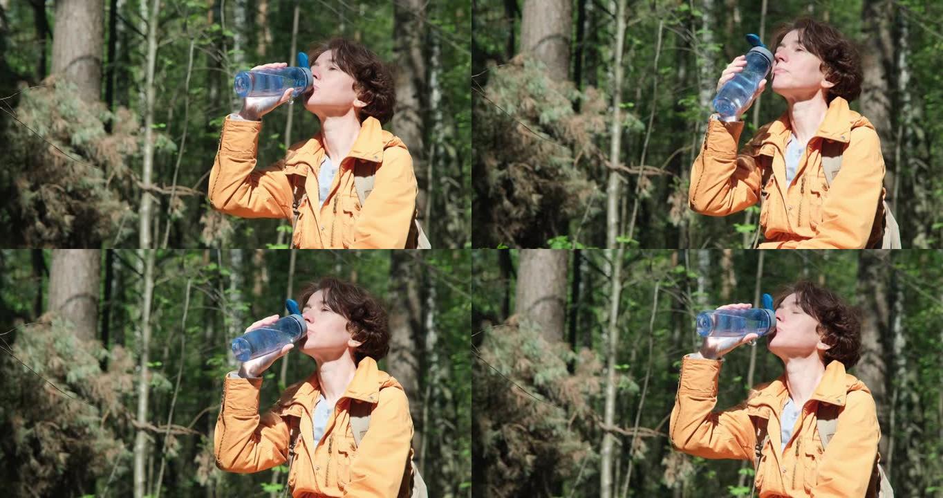 女人在阳光明媚的森林散步时喝水
