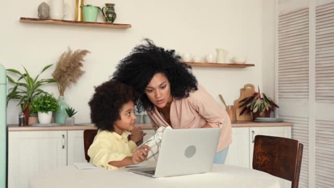 专注于美国黑人的女学生，使用笔记本电脑在家远程在线学习。小女孩在视频课上学习，并在笔记本上做笔记。慢