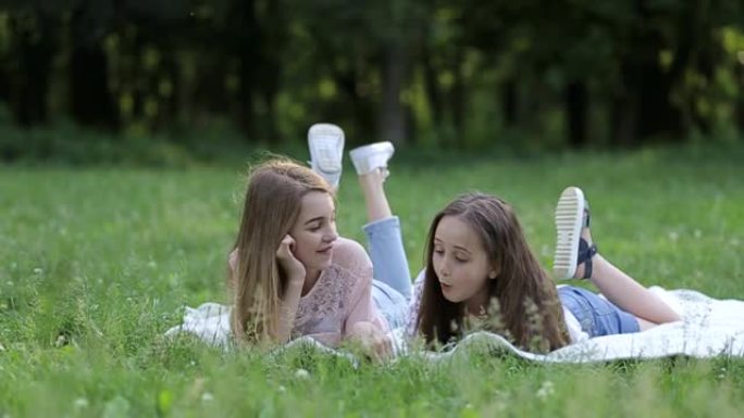 两个可爱的小姐妹在阳光明媚的夏日一起在草地上玩得开心