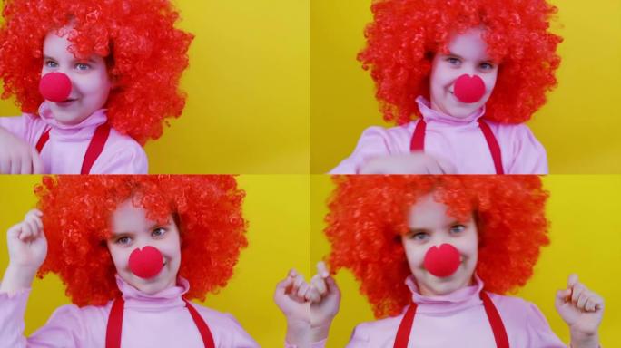 鼻子和头发红的滑稽小丑女孩孩子在黄色背景上旋转跳舞。4月1日愚人节，生日概念。