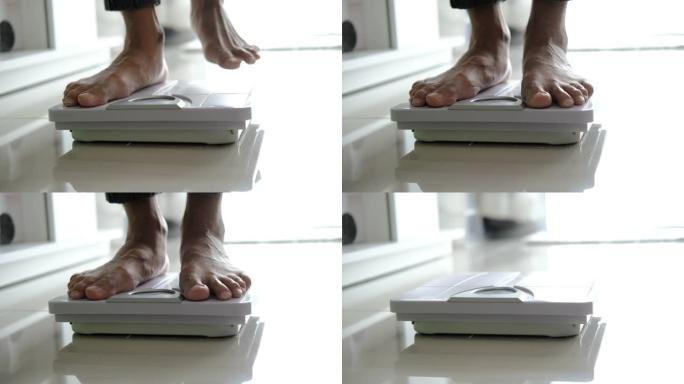 亚洲足部男子与体重体重秤，用于测量体重减轻。称重秤健康减肥概念。中长镜头平移娃娃移动焦点多莉滑块，用