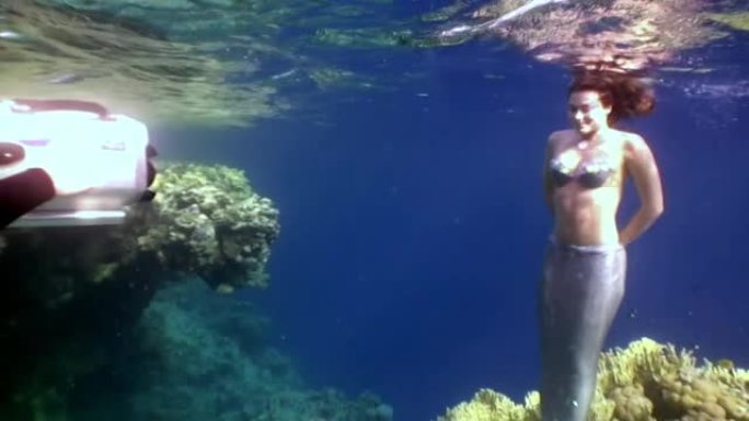 摄影师拍摄视频年轻女子水下模型美人鱼。