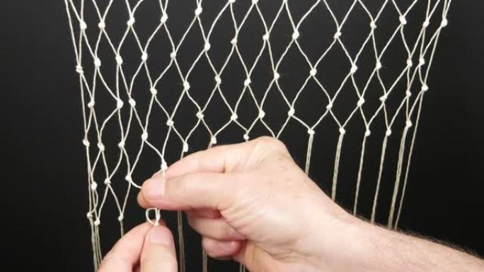人的手用白色合成绳，编织网，手工制作