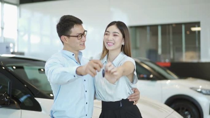 慢莫微笑的年轻夫妇展示车钥匙
