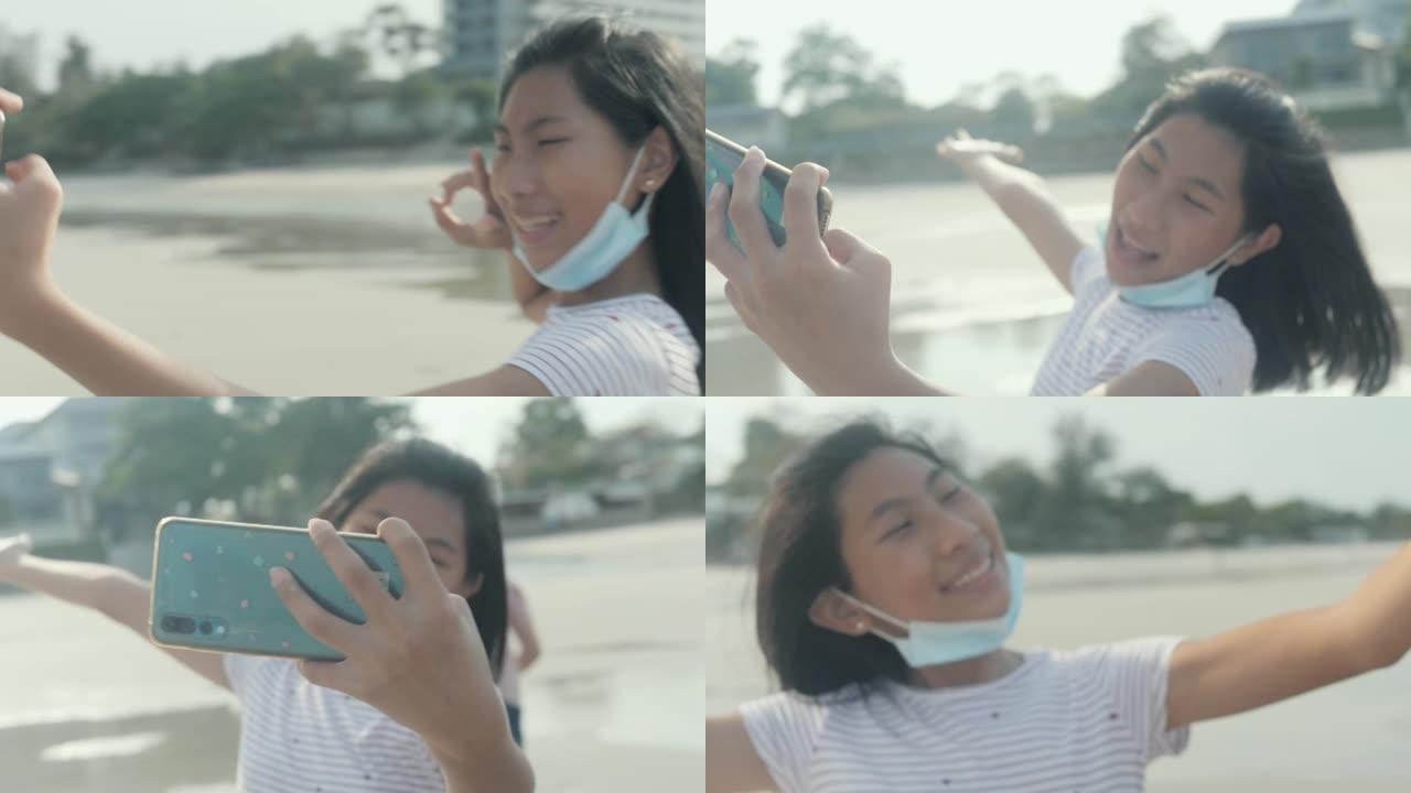 快乐的亚洲女孩自拍和视频通话给家人，同时在海滩上放松，生活方式理念。