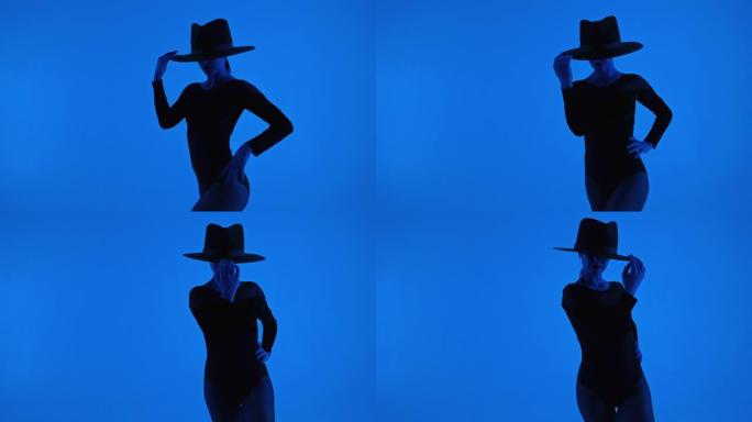 惊人的女士孤立在蓝色背景。戴帽子的专业舞者在摆姿势时表现出当代元素。性感的女人戴着帽子。高质量4k镜