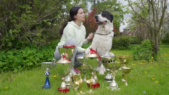 女宠物主人和她的获胜者中亚牧羊犬与狗一起颁奖，女子与阿拉巴伊在获胜杯附近