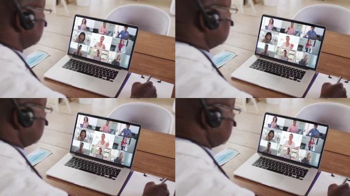 非裔美国男性医生在笔记本电脑上进行视频会议时做笔记