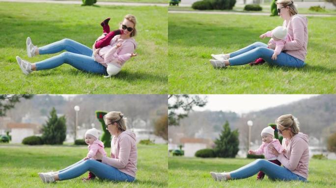 一位年轻的母亲正坐在草地上，和她的孩子玩耍。带着孩子在公园里娱乐。实时