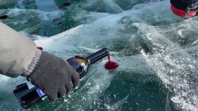 贝加尔湖之吻是游客的娱乐。一名男子将葡萄酒倒入冰冻的贝加尔湖的临时玻璃杯中。