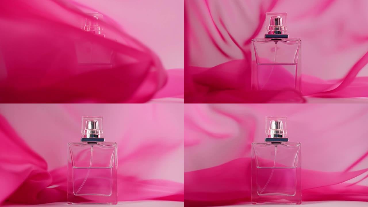 桌上摆着带有青色香水或精油的扁平香水瓶。粉红色的织物四处飘动，香水瓶周围的空气中飘扬。香气和气味的概