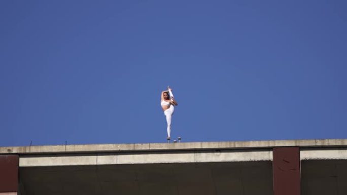 灵活的女人在建筑边缘保持1英尺的平衡。风险、勇气和机会概念