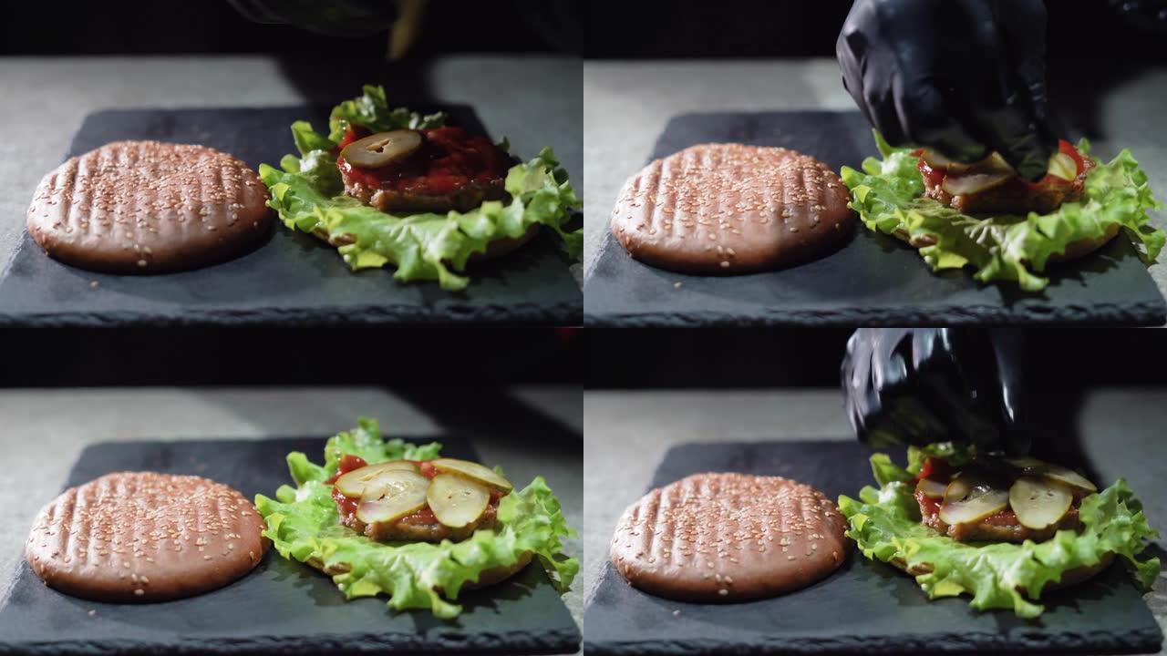 制作美味汉堡或芝士汉堡的过程。特写厨师的手套手将腌制的黄瓜放在炸肉排上。